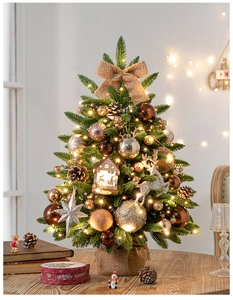 Close-up of mini Christmas tree with gold ornaments, warm LED lights and burlap base
