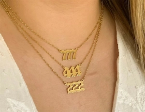 Close-up of layered 14K gold stainless steel necklaces with 777, 444, and 222 pendants