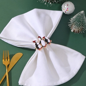 Christmas penguin napkin rings in gold metal and enamel set on a festive table