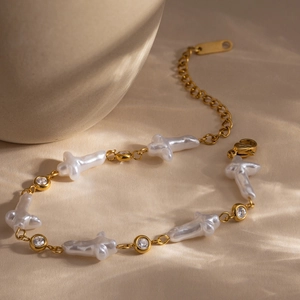 Dettaglio di bracciale in acciaio inossidabile 18K con perle a croce e zirconi lucidi