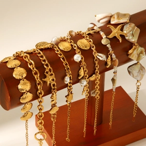 Detailed display of gold sea shell and starfish charm bracelets on a wooden stand