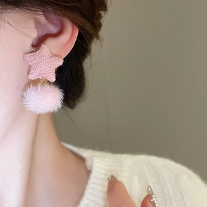 Nahaufnahme pinkfarbener Sternen-Ohrringe aus Stoff mit flauschigem Plüsch-Pompon