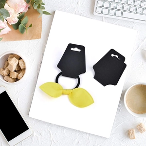 Blank jewelry display cards with a yellow bow hair tie and black elastic band on white background