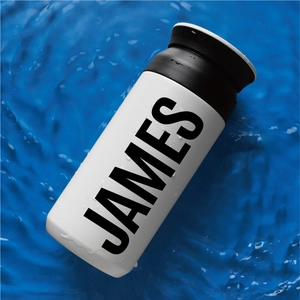 Close-up of white insulated water bottle with black JAMES lettering and water droplets
