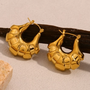 Detail view of 18K gold plated hollow earrings with ripple texture on dark wood stand