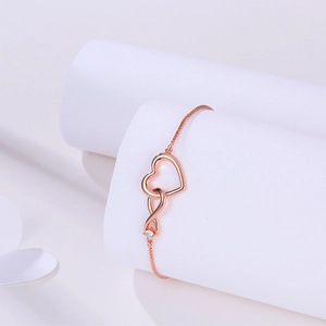 Detail of rose gold bracelet with heart and infinity symbol set with zircon stones