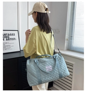 Detailed view of light blue quilted travel bag with adjustable strap and diamond pattern