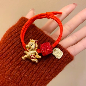 Détail d'élastique à cheveux rouge avec pendentif cheval doré et strass rouges brillants