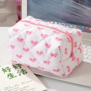 Détail de la trousse de maquillage matelassée à motifs de nœuds sur un clavier