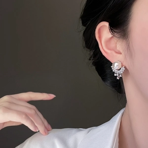 Detail of silver needle pearl earrings with micro-inlaid rhinestones on a female model
