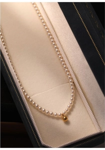 Detailed macro of a freshwater baby pearl choker with a polished 14K gold bead pendant