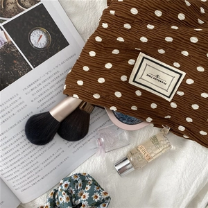 Detailed texture of brown polka dot pleated fabric cosmetic bag with a zipper closure