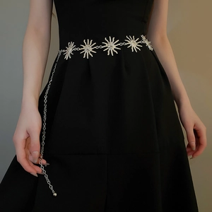 Detail van vintage zilveren metalen heupketting met zonpatronen op een zwarte jurk