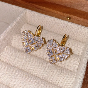 Gros plan détaillé de boucles d'oreilles cœur dorées avec cristaux zircons sur velours
