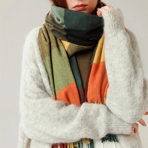 Elegant striped plaid shawl scarf with tassels worn by a model over a grey cardigan