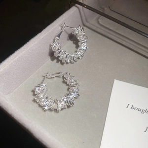 Close-up of irregular silver hoop earrings with pavé stones in a velvet jewelry box