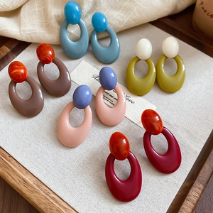 Detail view of colorful oval resin acrylic earrings displayed on a rustic linen tray