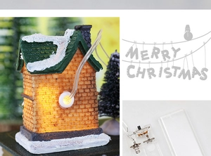 Detail view of glowing Christmas resin house showing warm lights and battery compartment