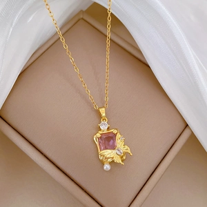 Macro detail of golden butterfly pendant with pink gemstone and small pearl on jewelry box