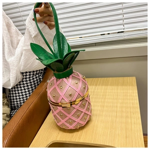 Detailed view of pink pineapple crossbody bag with gold rivets and green leaf handle