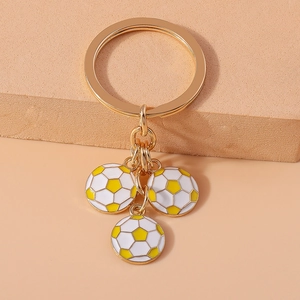 Detailed macro shot of three yellow and white soccer ball pendants on a gold keychain