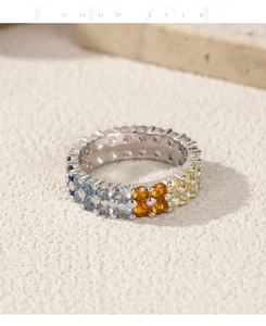 Macro shot of double row rainbow gemstone pavé ring on a textured stone surface
