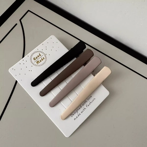 Set of four matte seamless duckbill hair clips in brown and beige tones on display card