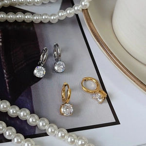 Macro shot of gold and silver hoop earrings featuring large round-cut sparkling zircons