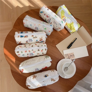 Various cute quilted cotton pencil cases with floral and animal prints on a wooden desk