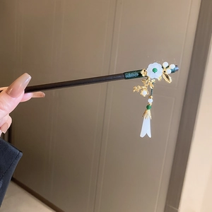 Detail of wooden hair stick featuring white flower, golden leaves and green beads
