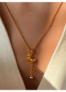 Close-up of gold plated horse and coin pendant necklace worn with a white knit top
