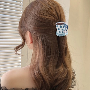 Detailed view of an acrylic coffee cup hair claw clip with blue flower patterns