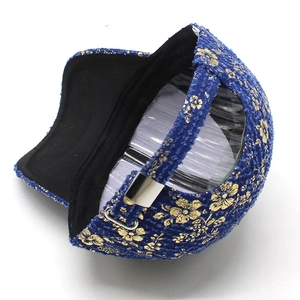 Detailed view of gold floral embroidery on denim baseball cap with metal buckle closure