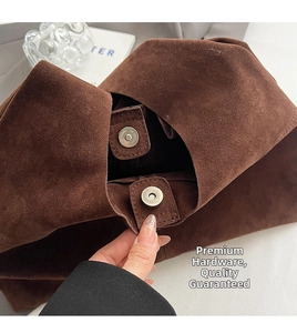 Close-up of circular metal magnetic closure on brown suede tote bag with fine texture
