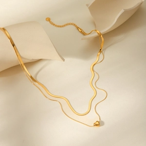 Detail of 18k gold double-layer snake chain necklace with small heart pendant on stone