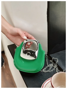 Close-up of vibrant green mini handbag with silver metal handle and chain strap