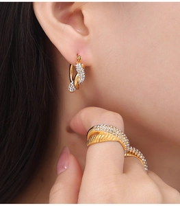 Detailed close-up of a gold-plated twisted ring and matching hoop earrings with rhinestones