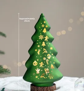 Detail of green frosted glass Christmas tree with gold snowflake patterns and a wood base