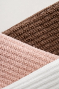 Close-up of soft ribbed knit combed cotton texture in brown, pink, and white colors