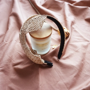 Top view of a raffia straw braided headband with black fabric trim on a neutral background
