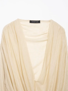 Detailed view of deep V-neckline on beige ruched long sleeve top showing fabric texture