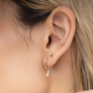 Detail of S925 silver gold earrings set with purple gems and shell pendant on ear