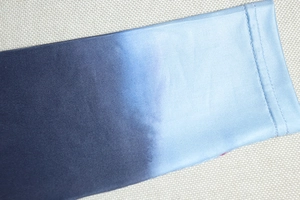 Dettaglio del polsino sfumato blu in maglia elastica con cuciture ad ago doppio