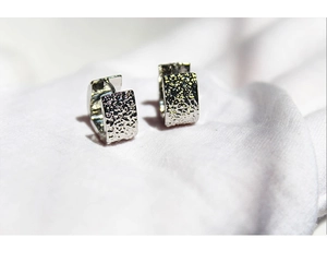 Detailed view of silver rectangular hoop earrings featuring a unique hammered metal texture
