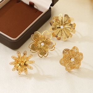 Détail de bagues fleurs dorées ajourées avec perles blanches sur boîte à bijoux
