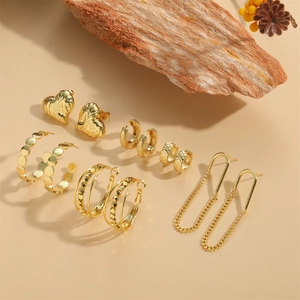 Luxury gold heart earrings and hoop set with vintage chain designs on wood