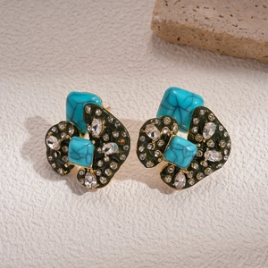 Detail of geometric acrylic earrings with turquoise stones and rhinestone accents