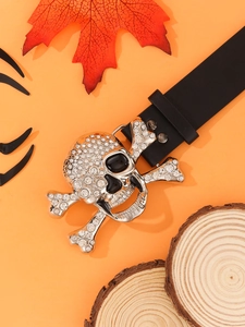 Punk style black leather belt with silver skull buckle on autumn leaf background