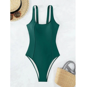Flat lay of deep green high-cut swimsuit with square neck, straw hat, and sunglasses on marble