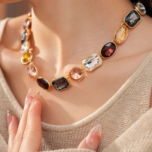 Dettaglio della collana vintage dorata con strass misti indossata da una modella